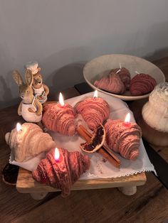 a table topped with pastries and candles on top of a wooden tray next to other items