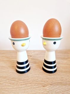 two egg cups with black and white stripes on them, one has an egg in the middle