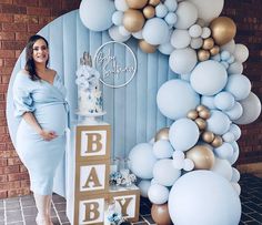 a pregnant woman standing in front of a backdrop made out of balloons and baby blocks