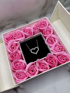 a box with pink roses and a necklace in the shape of a heart on it