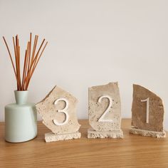 three stone numbers sitting on top of a table next to a vase with sticks in it