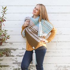 a woman standing in front of a white wall wearing a crocheted shawl