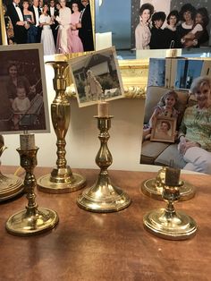 three golden candlesticks on a table with pictures and family photos in the background