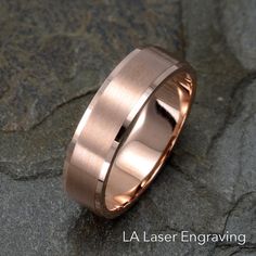 a rose gold wedding band on top of a rock