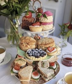 three tiered trays filled with sandwiches and pastries on top of a table