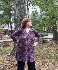 a woman standing in front of a tree with her hands on her hips and looking up