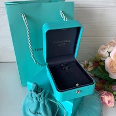 an open tiffany co ring in a blue gift box next to flowers and a bouquet