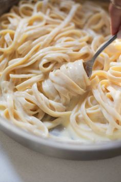 someone is cutting up some noodles in a bowl