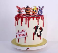 a birthday cake decorated with cartoon characters and blood dripping down the top, on a white surface