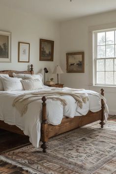 a bed with white sheets and pillows in a bedroom next to a window on an antique rug