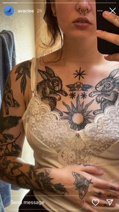 a woman with tattoos on her chest holding a cell phone