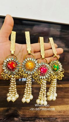 three pairs of gold tone earrings with multicolored stones and pearls hanging from each ear