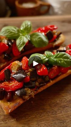 two pieces of bread with tomatoes, olives and basil