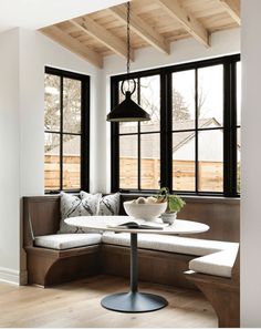 a white table and some black windows in a room with wood flooring on the walls