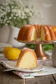 a bundt cake on a plate with lemons and flowers in the back ground