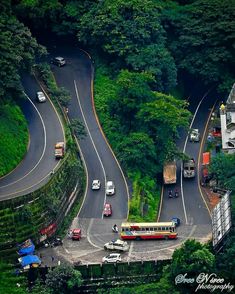 an aerial view of cars and buses on a road in the middle of a forest