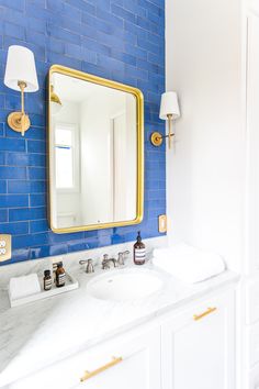 a bathroom with blue brick walls and gold trim on the mirror above the double sink