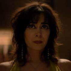 a woman in a yellow dress looking at the camera with an intense look on her face