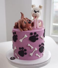 a pink cake decorated with dogs and bones