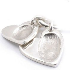 two silver heart shaped pendants with fingerprints on the front and back of them