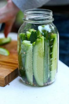 cucumber slices are in a glass jar on a cutting board