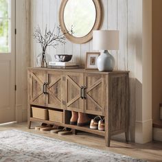 a wooden cabinet with shoes on it and a round mirror hanging above the door way