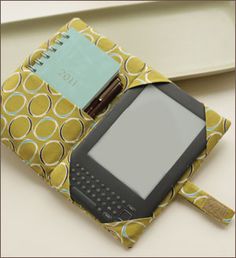 an electronic device sitting on top of a yellow and white bag with a note pad