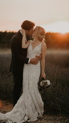 a bride and groom kissing in an open field at sunset