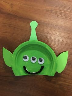 a green paper plate with googly eyes and a leaf on it's head