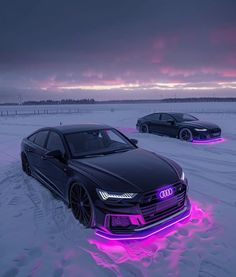 two cars parked in the snow with purple lights on them and one car is black