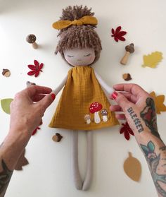 a handmade doll is being held by two hands