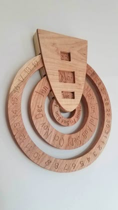 three wooden circles with numbers on them hanging from the wall in front of a white wall