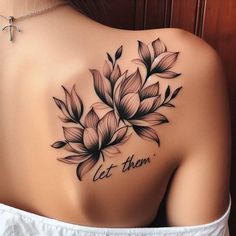 a woman's back tattoo with flowers and the words let them written on it