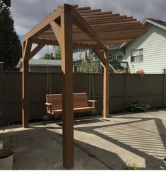 a wooden pergolan sitting in the middle of a yard next to a house