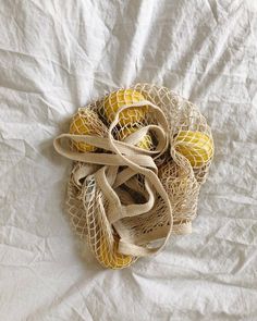 three balls are in a mesh bag on a white sheeted surface, one is yellow and the other is brown