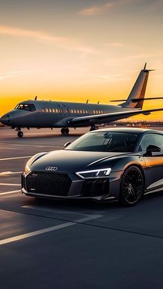 an audi sports car on the tarmac with a plane in the background at sunset