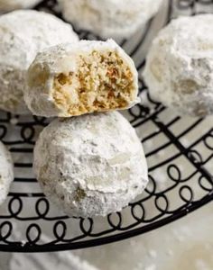 powdered sugar balls on a wire rack with one cut in half to show the inside