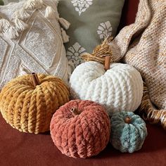 crocheted pumpkins are sitting on a couch next to some pillows and blankets