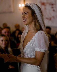 a woman in a wedding dress smiles as she holds her hand out to the groom