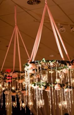 the chandelier is hanging from the ceiling with flowers and lights all around it