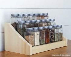 a wooden shelf holding glass jars filled with different types of spices and seasonings on it