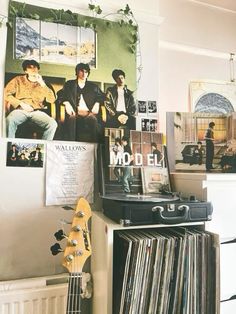 a room with various records and pictures on the wall, including an electric guitar sitting next to a record player