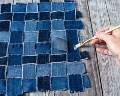 someone is painting the fabric with paintbrushes on a wooden surface, next to a piece of denim