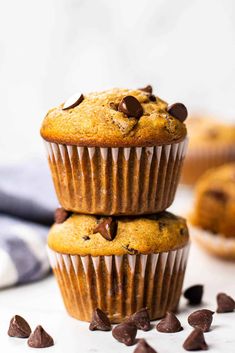 three chocolate chip muffins stacked on top of each other with scattered chocolate chips