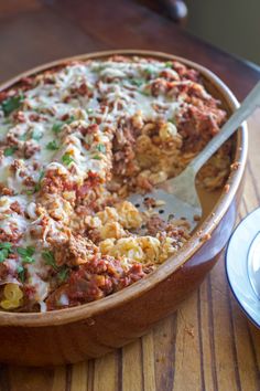 a casserole dish with meat, cheese and vegetables in it on a wooden table