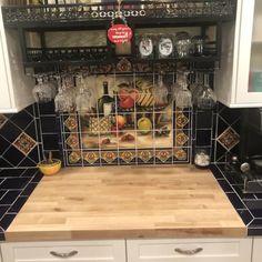 a kitchen counter with some wine glasses on top of it and a wooden cutting board