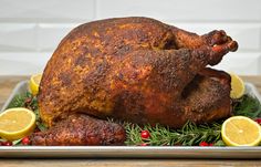 a roasted turkey on a platter with lemons and cranberry garnish