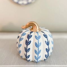 a blue and white ceramic pumpkin sitting on top of a table next to a clock