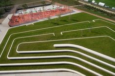 an aerial view of a park with grass and concrete ramps, trees, and playground equipment