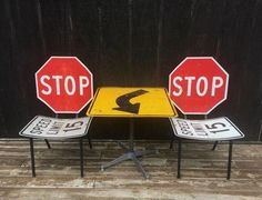 two stop signs are sitting next to each other on top of a table with another sign in front of them